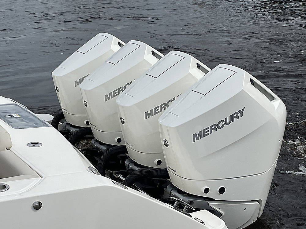Four white Mercury outboards mounted across the transom of a boat on the water