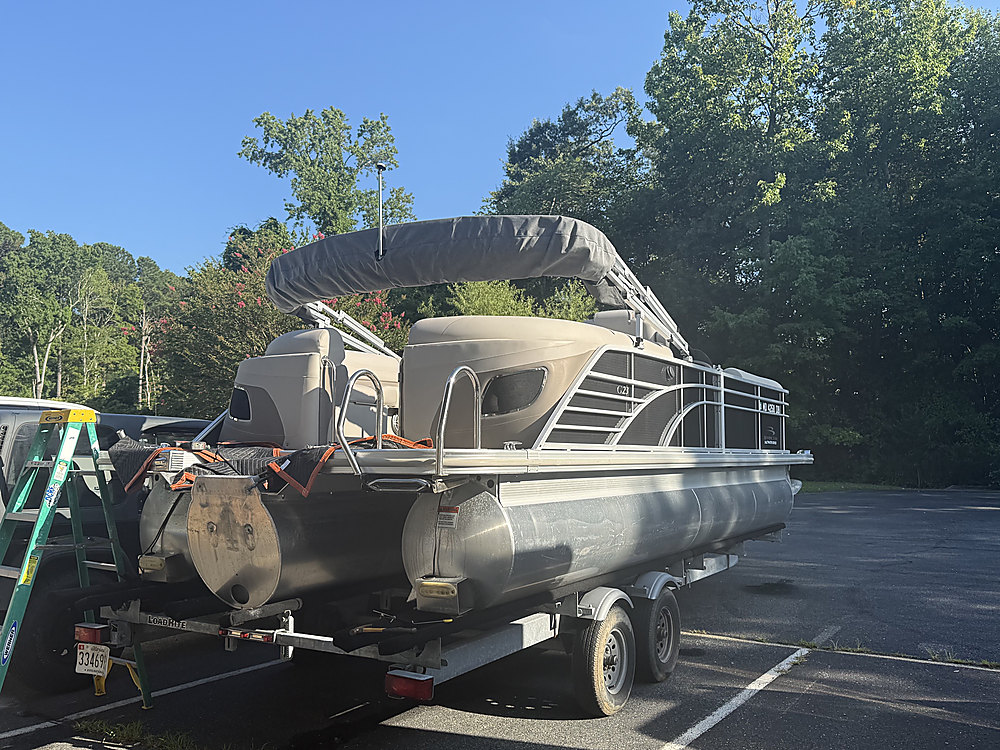 The pontoon boat on its trailer in the yard with the transom bare
