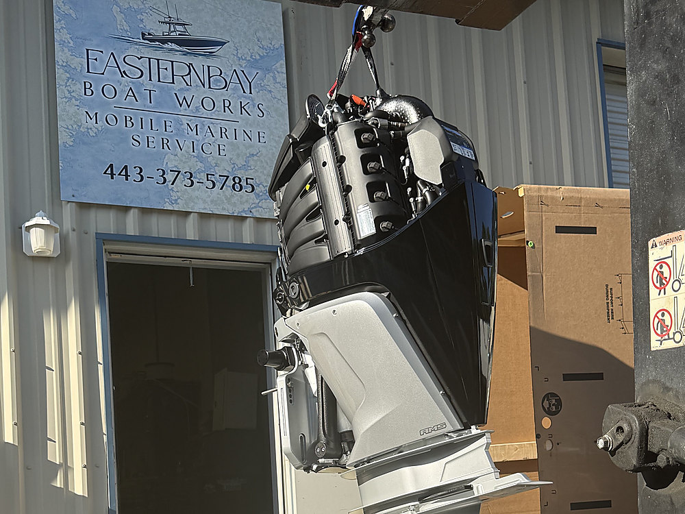 The new Mercury outboard hanging on the hoist under the Eastern Bay Boat Works sign