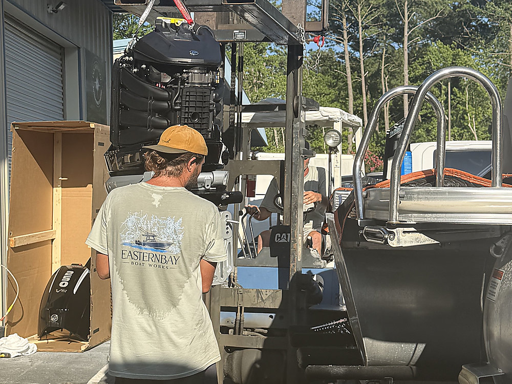 An Eastern Bay Boat Works technician moving the new outboard out to the boat